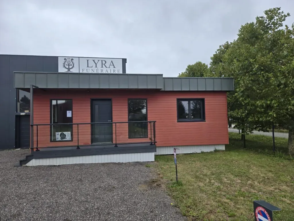 Façade de l'agence Lyra Funéraire avec bardage en bois rouge et rampe d'accès PMR