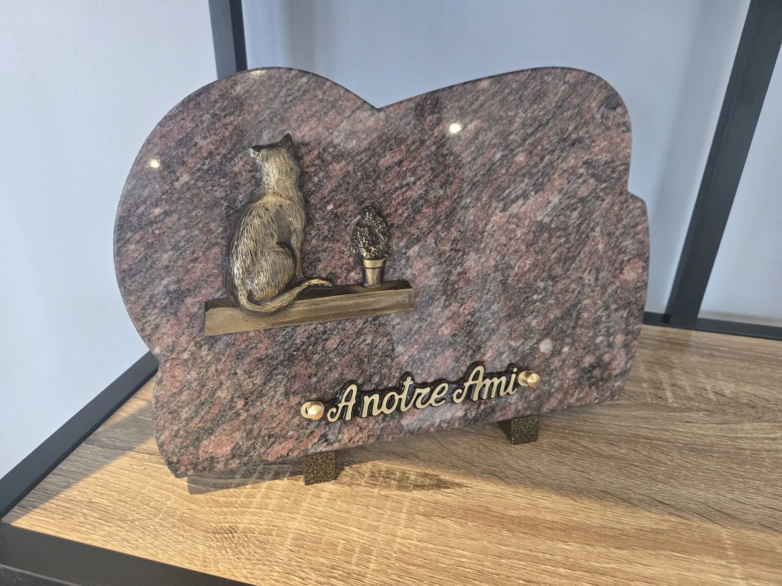 Plaque funéraire en granite rose avec motif sculpté de chat et inscription