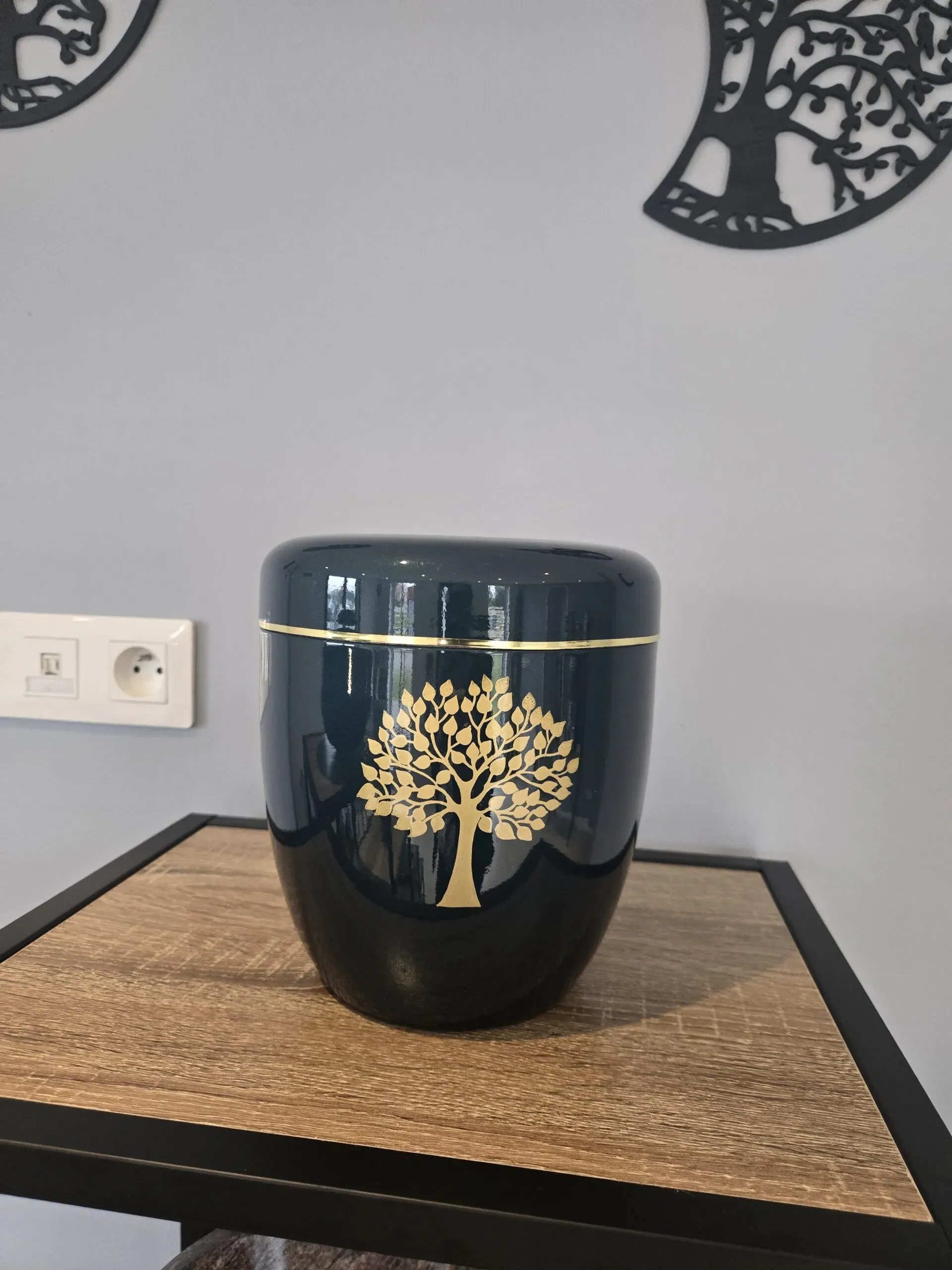 Urne funéraire cinéraire sombre ornée de la dorure d'un arbre de vie.