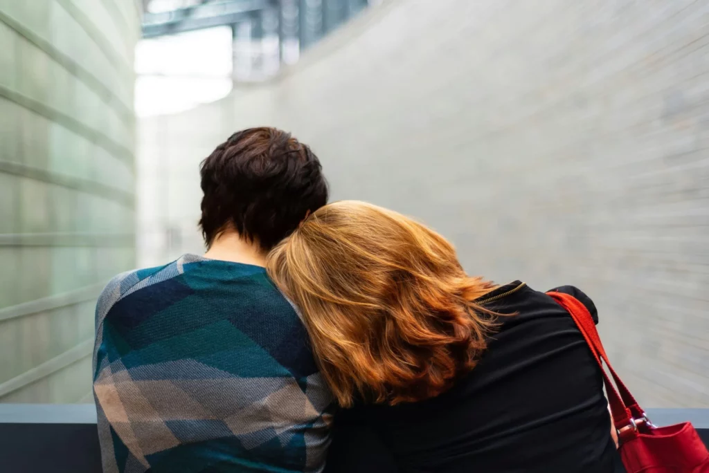 Une femme posant doucement sa tête sur l'épaule d'une autre personne en signe de soutien